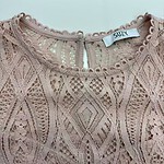 Close-up of a pink lace dress with intricate patterns and a keyhole back closure, perfect for stylish occasions.