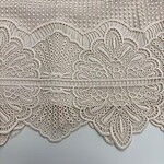 Close-up of intricate beige lace fabric with detailed embroidery and patterns, ideal for fashion and wedding dress design.