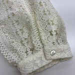 Close-up of an elegant ivory lace sleeve with a pearl button, showcasing intricate floral lace pattern and delicate craftsmanship.