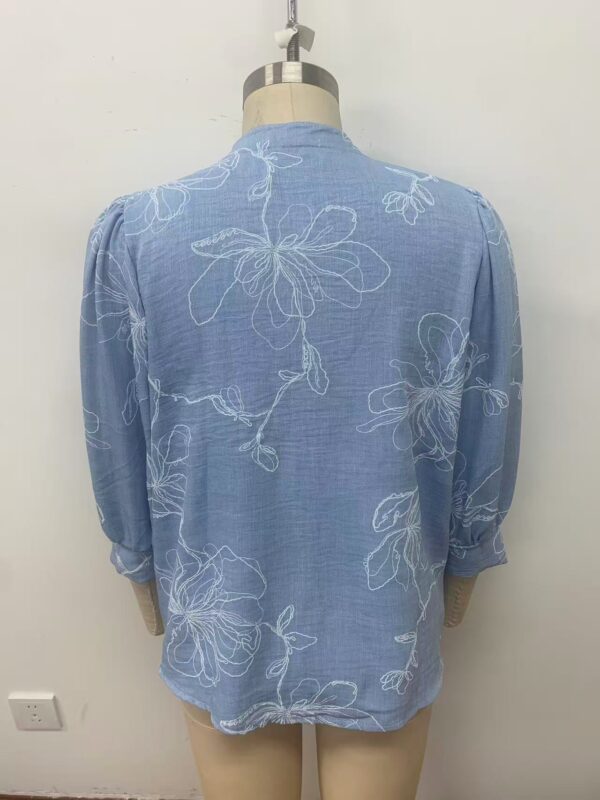 Light blue women's blouse with white floral embroidery, long sleeves, and a relaxed fit, perfect for casual or semi-formal occasions.