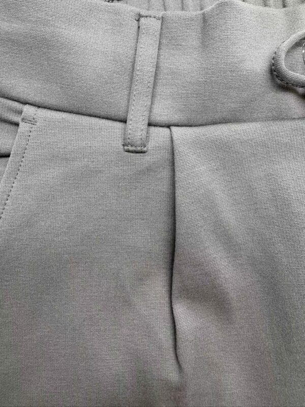 Close-up of stylish grey men's trousers showing waistband and fabric texture, ideal for formal or business casual wear.
