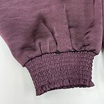 Close-up of a burgundy sweatshirt sleeve with elasticated cuff, showcasing soft fabric and casual style, ideal for fashion and apparel SEO.
