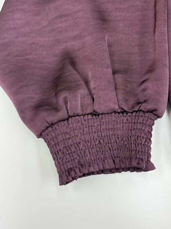 Close-up of a burgundy sweatshirt sleeve with elasticated cuff, showcasing soft fabric and casual style, ideal for fashion and apparel SEO.