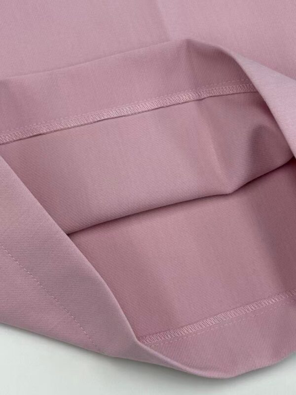 Close-up of a pink fabric bag with a smooth texture and stitched edges, ideal for storing fashion accessories or personal items.