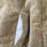 Detailed image of a beige suede jacket pocket with white lining, showcasing the texture and craftsmanship of the outer material.