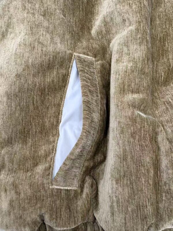 Detailed image of a beige suede jacket pocket with white lining, showcasing the texture and craftsmanship of the outer material.