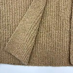 Close-up of a beige knitted sweater with a folded sleeve, showcasing soft texture and fine ribbing, perfect for fall and winter fashion.