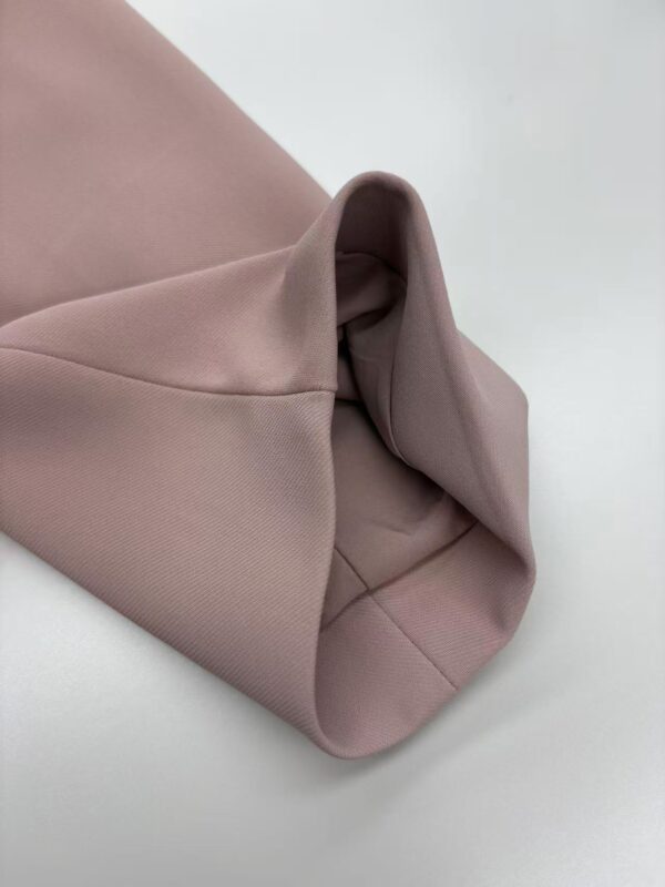 Close-up of blush pink fabric with smooth texture and folded design, showcasing high-quality material and craftsmanship.