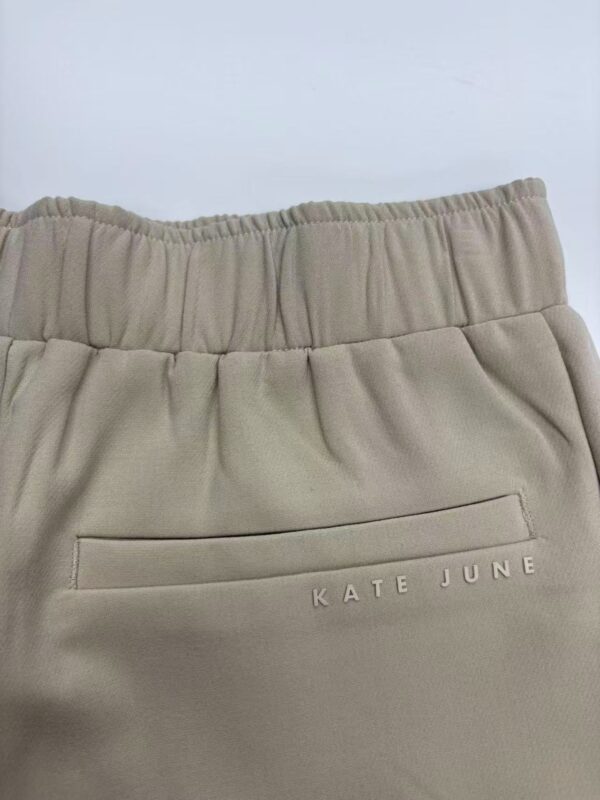 Close-up of beige casual joggers with elastic waistband and back pocket featuring 'KATE JUNE' branding, perfect for comfortable everyday wear.