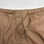 Close-up of beige casual pants with elastic waistband and drawstring for adjustable fit.