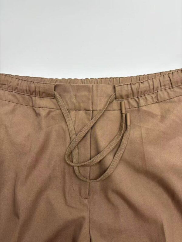 Close-up of beige casual pants with elastic waistband and drawstring for adjustable fit.
