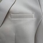 Close-up of a light grey blazer with a sleek pocket design, perfect for formal or business attire, showcasing high-quality fabric and craftsmanship.