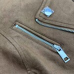 Close-up of a beige jacket featuring a silver zipper and a decorative button, highlighting fashion and clothing details.