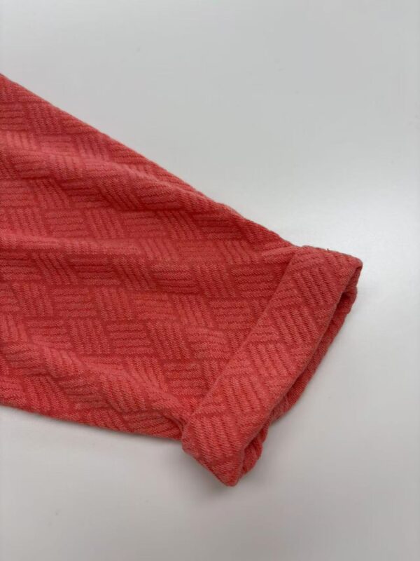 Close-up of a red textured fabric with geometric pattern, ideal for fashion and clothing design.