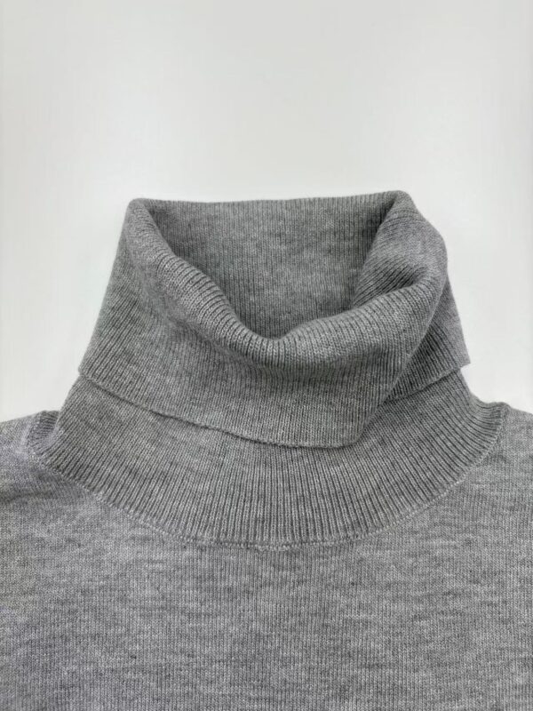 Close-up of a gray turtleneck sweater, showcasing the soft knit fabric and high collar design, ideal for fall and winter fashion.