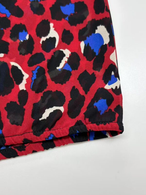 Close-up of vibrant leopard print fabric with red, black, white, and blue spots, showcasing a stylish and bold pattern for fashion apparel.