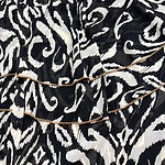 Close-up of a black and white animal print dress with gold chain accessories, showcasing trendy fashion details.