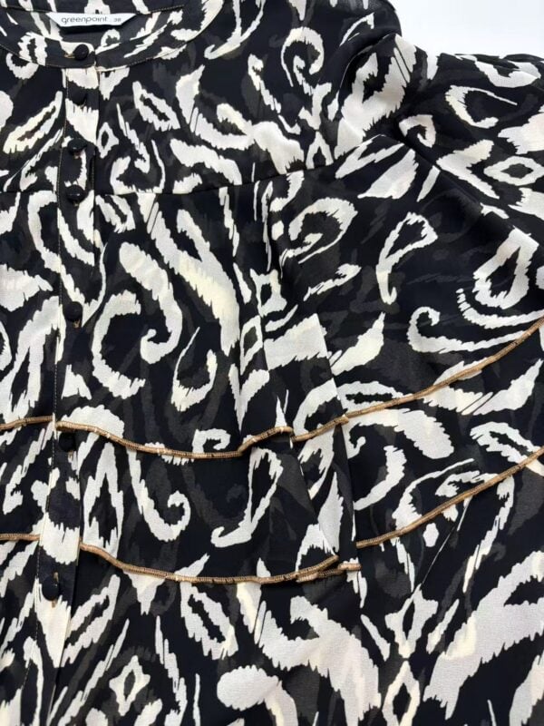 Close-up of a black and white animal print dress with gold chain accessories, showcasing trendy fashion details.