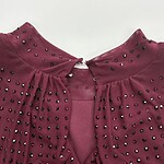 Close-up of a burgundy dress featuring rhinestone embellishments on the shoulders and neckline, perfect for stylish occasions.