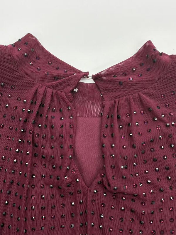 Close-up of a burgundy dress featuring rhinestone embellishments on the shoulders and neckline, perfect for stylish occasions.