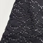 Close-up of a black dress with intricate beadwork and embroidery, perfect for evening wear and special occasions.
