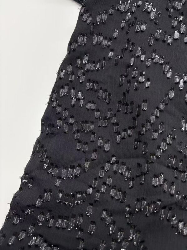 Close-up of a black dress with intricate beadwork and embroidery, perfect for evening wear and special occasions.