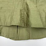 Close-up of olive green linen fabric showing texture and stitching details, ideal for fashion and textile enthusiasts.