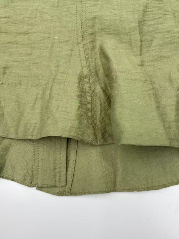 Close-up of olive green linen fabric showing texture and stitching details, ideal for fashion and textile enthusiasts.