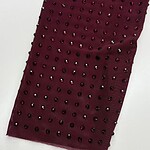 Close-up of burgundy fabric adorned with small black rhinestones, perfect for luxury fashion or evening wear.