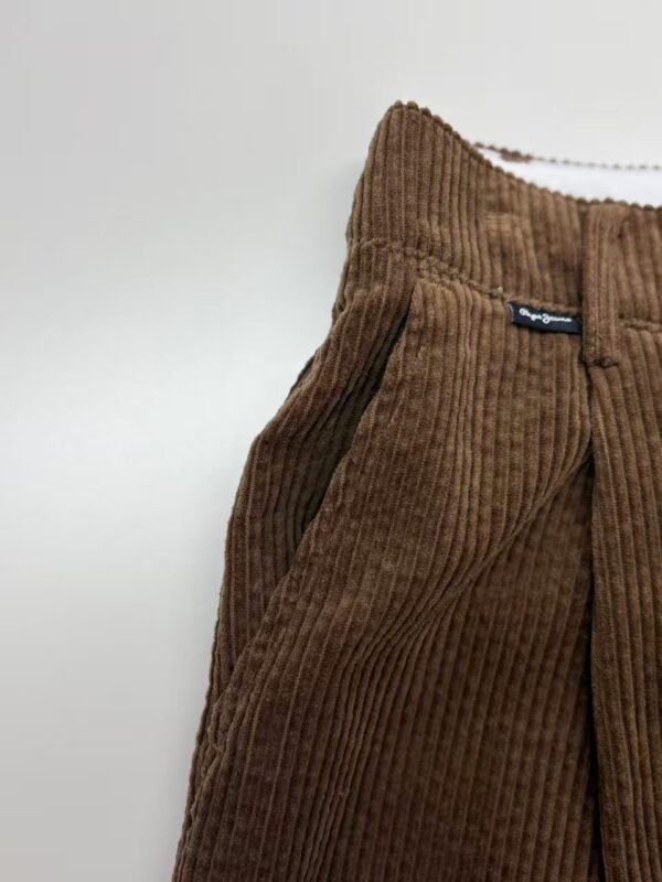 Close-up of brown corduroy pants with a high waist and side pockets, showcasing textured fabric and stylish design.