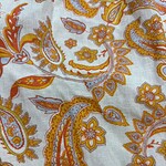Close-up of a vibrant paisley fabric with orange, yellow, and white floral and paisley motifs, showcasing intricate design details.