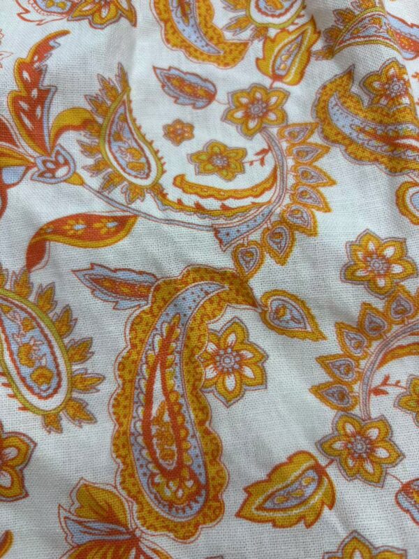 Close-up of a vibrant paisley fabric with orange, yellow, and white floral and paisley motifs, showcasing intricate design details.