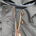 Close-up of stylish grey pants featuring a gold zipper and buttons, showcasing high-quality fabric and modern design for fashion-forward individuals.