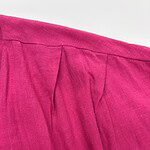 Close-up of a vibrant pink linen skirt with pleats, showcasing high-quality fabric and craftsmanship, perfect for stylish summer or casual wear.