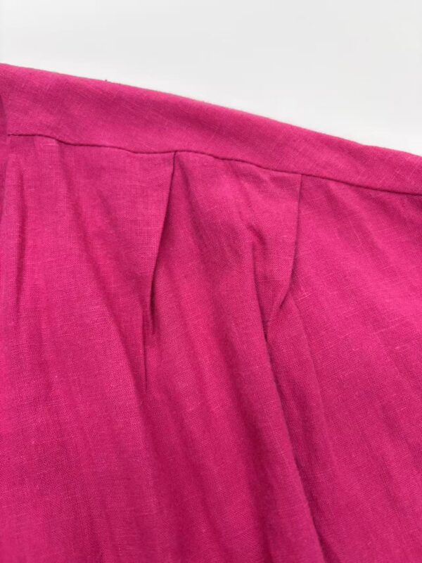 Close-up of a vibrant pink linen skirt with pleats, showcasing high-quality fabric and craftsmanship, perfect for stylish summer or casual wear.