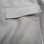 Close-up of a light grey fabric with a stylish pocket featuring a flap, showcasing high-quality material and craftsmanship.