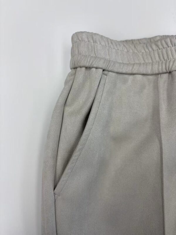 Close-up of grey sweatpants with elastic waistband and side pocket, suitable for casual wear and loungewear.