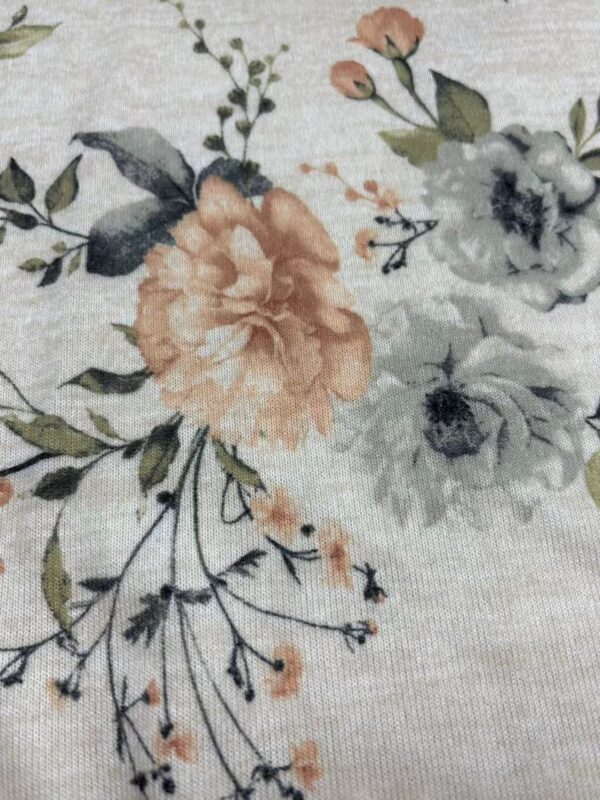 Close-up of floral fabric with peach, white, and gray flowers and green leaves, ideal for fashion and textile projects.