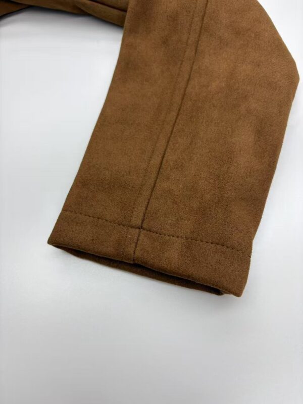 Close-up of brown suede fabric with visible stitching, highlighting texture and quality for fashion or upholstery use.