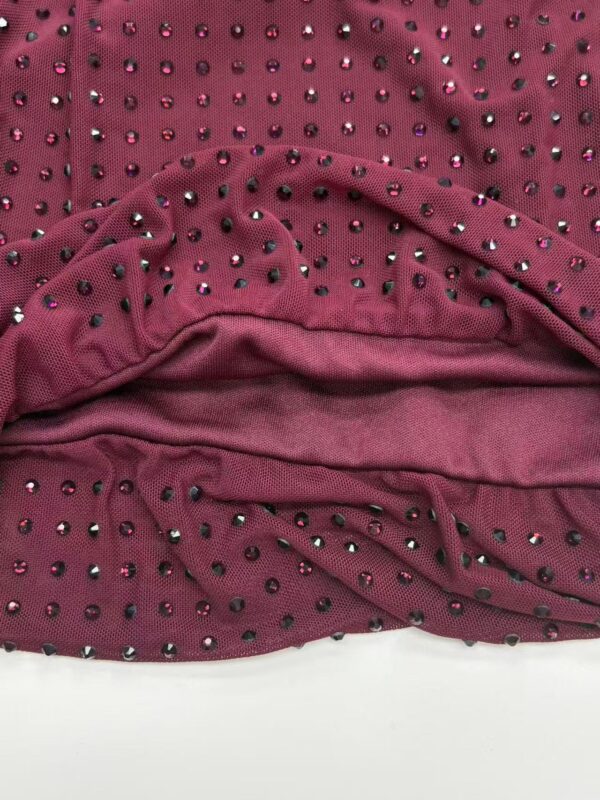 Close-up of burgundy fabric adorned with small rhinestones, showcasing a luxurious and stylish material suitable for fashion apparel and accessories.