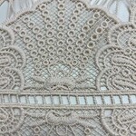 Close-up of intricate white lace fabric with detailed embroidery and patterns, ideal for fashion and textile projects.