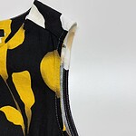 Close-up of a stylish black dress with bold yellow abstract patterns, showcasing high-quality fabric and stitching details for modern fashion.
