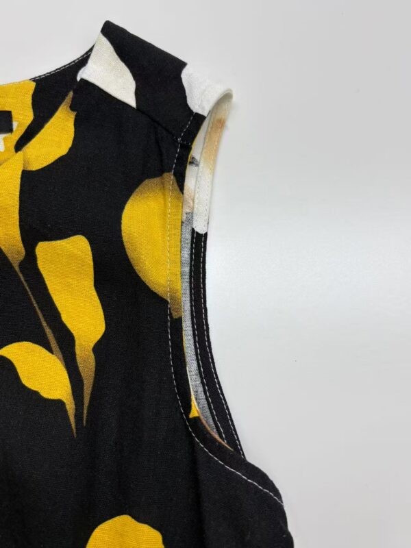 Close-up of a stylish black dress with bold yellow abstract patterns, showcasing high-quality fabric and stitching details for modern fashion.
