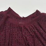 Close-up of a burgundy blouse featuring rhinestone embellishments on the neckline and pleated fabric details for a stylish look.