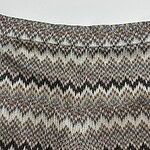 Close-up of fabric with multicolored zigzag pattern in earthy tones, showcasing detailed textile design.
