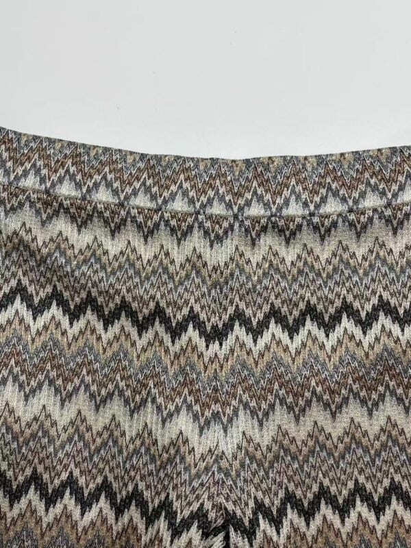 Close-up of fabric with multicolored zigzag pattern in earthy tones, showcasing detailed textile design.
