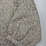 Close-up of luxurious brocade fabric with intricate gold and silver patterns, ideal for high-end fashion and special occasion garments.