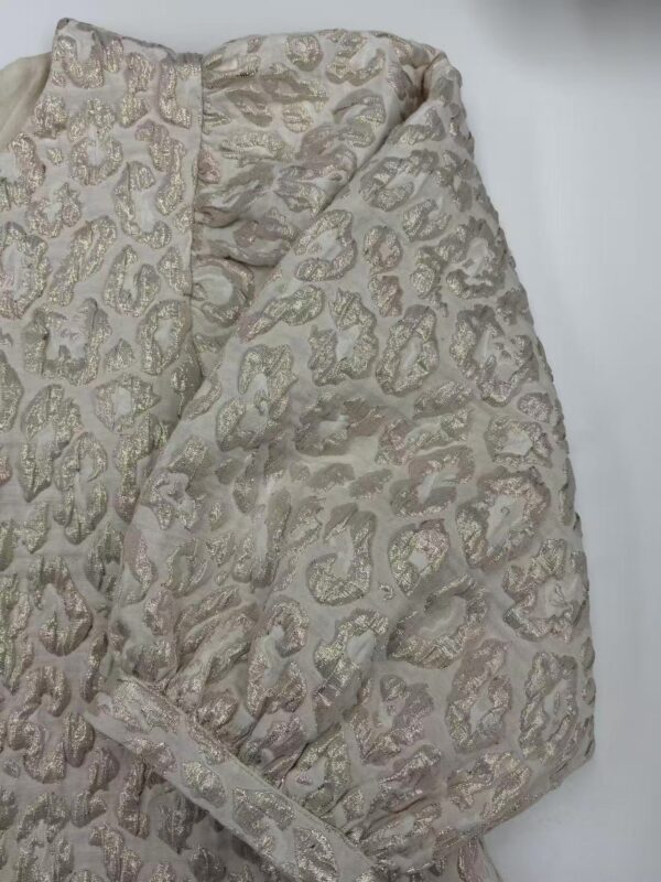 Close-up of luxurious brocade fabric with intricate gold and silver patterns, ideal for high-end fashion and special occasion garments.