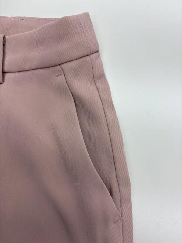 Close-up of stylish pink women's trousers with tailored fit and clean stitching, perfect for casual or office wear.