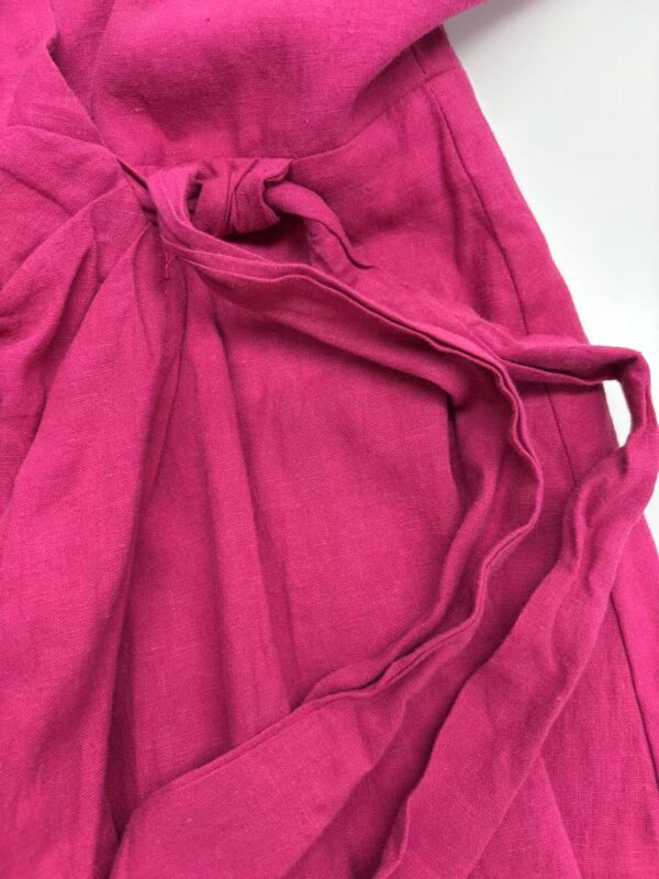 Close-up of a vibrant pink lounge robe made of soft fabric with a tied waist and pockets, perfect for comfortable home wear.